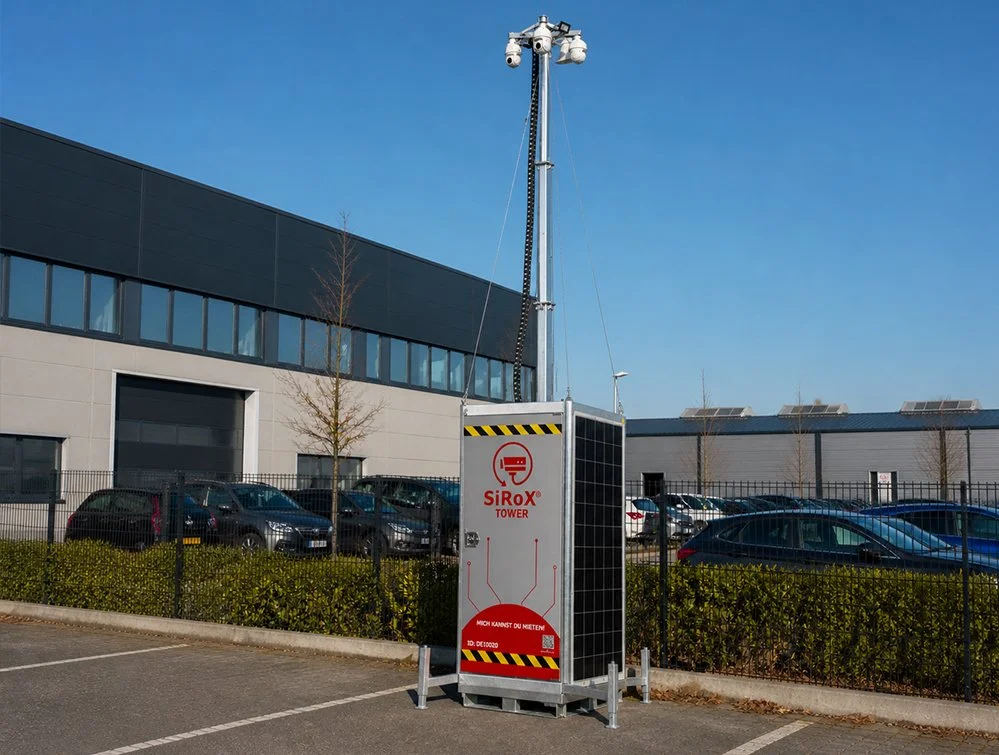 Ein Überwachungsturm mit Solarpanel und Kamera in einem Parkhausumfeld.