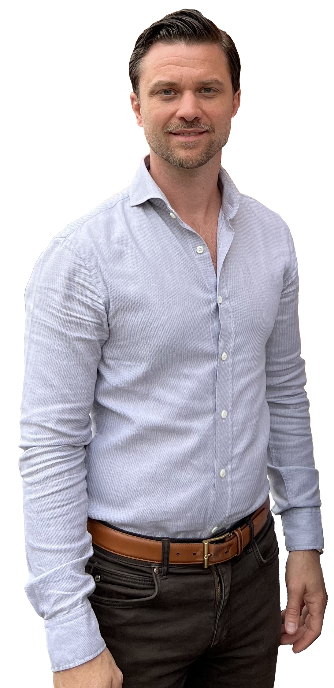 En man med ljusblå skjorta och brunt skärp står mot en svart bakgrund.