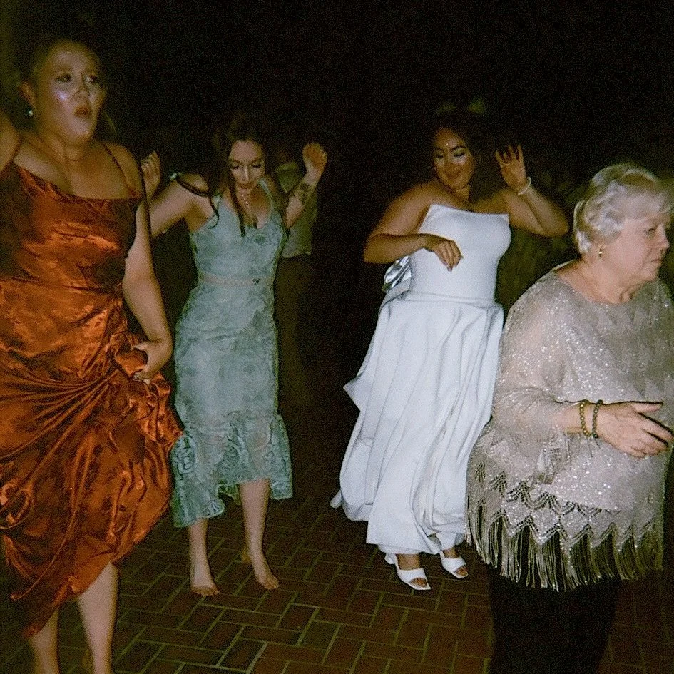Group of women at a celebration dance, wearing formal dresses.