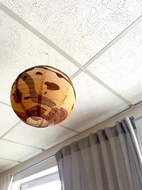 Papierlaterne an der Decke im Raum, im Hintergrund Vorhänge vor einem Fenster.