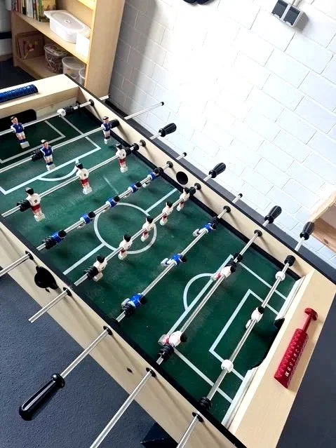 Tischfußballspiel mit mehreren Fußballfiguren auf einem grünen Spielfeld.