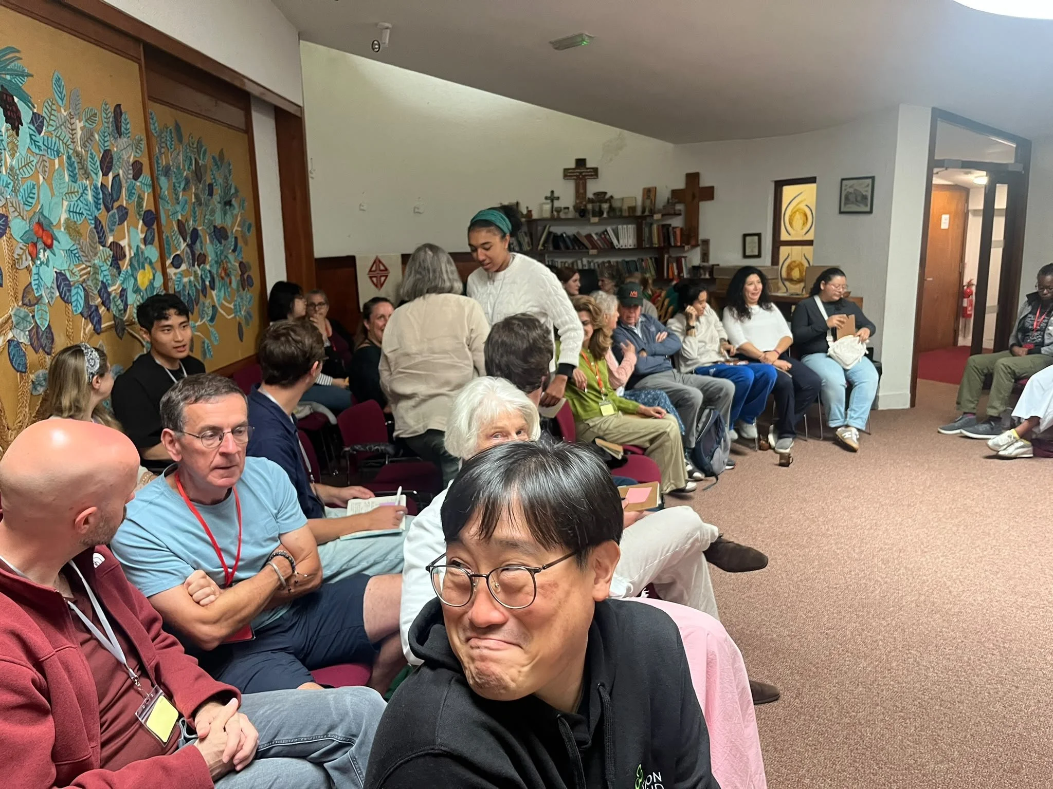A group of people seated in a room, engaged in conversations.