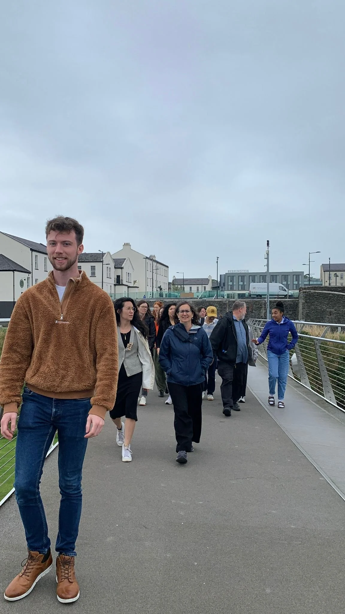 Group of people walking on a bridge outdoors on a cloudy day.