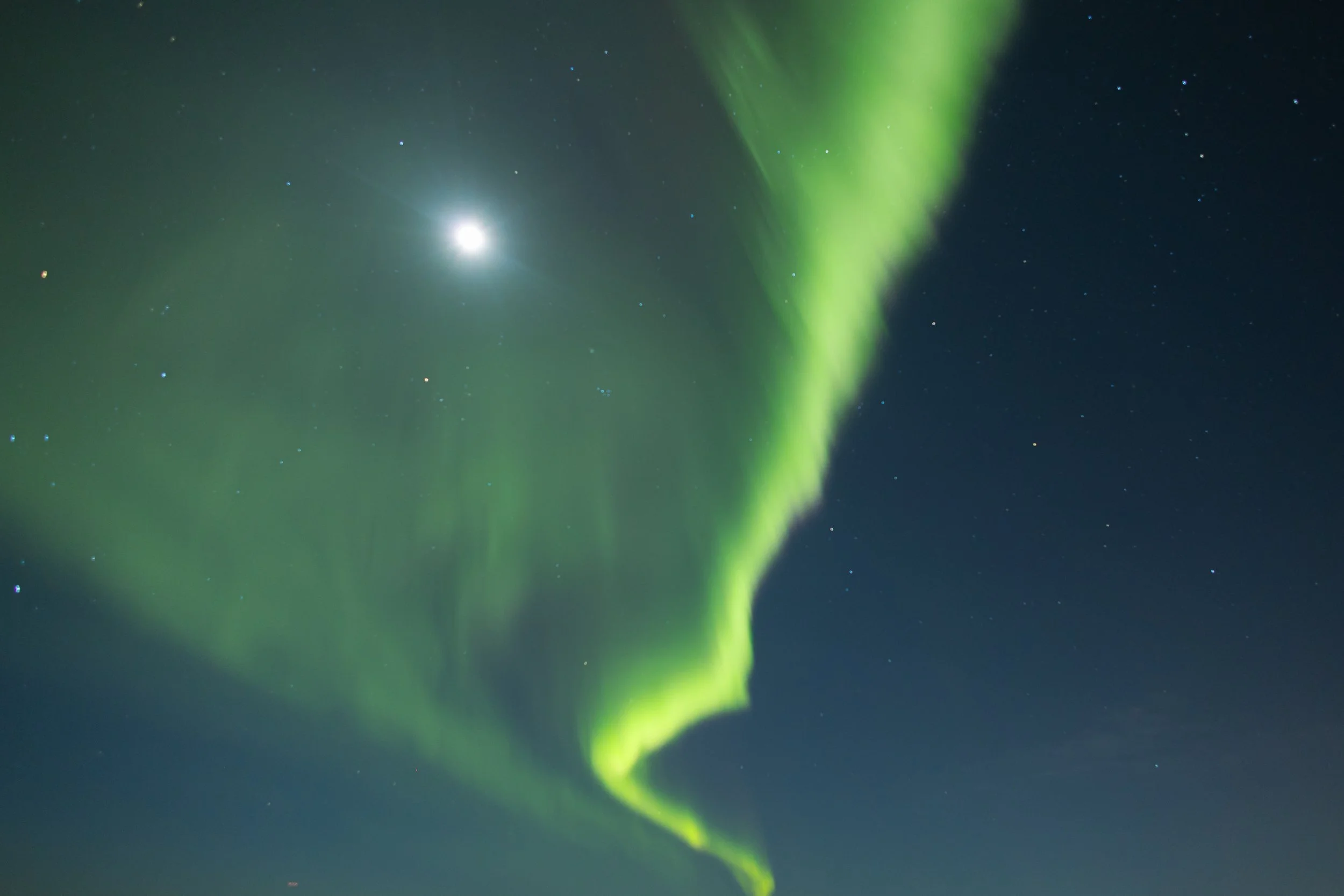 Northern lights in the night sky with the moon and stars.