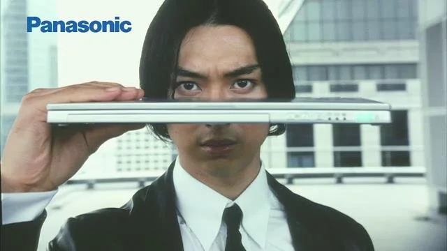 ビジネスマンがノートパソコンを水平に持ち上げている画像。背景は都市のビル群。左上にパナソニックのロゴがある。