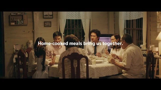 家族が暖炉のあるリビングルームで夕食を囲む様子。テーブルには料理や食器が並び、和やかな雰囲気。