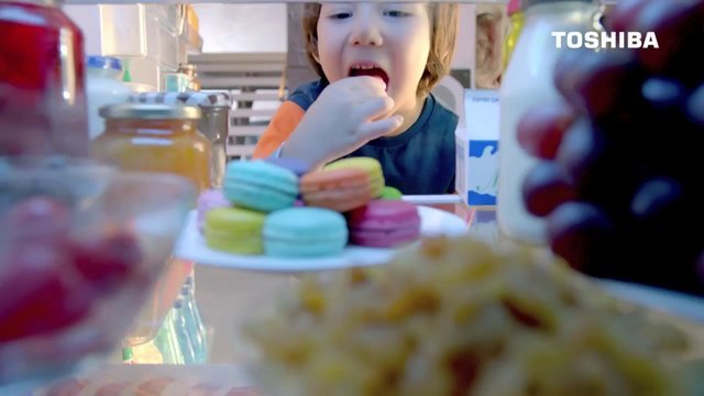 子供がケーキを食べている様子。前景に多彩なマカロンとケーキが見える。