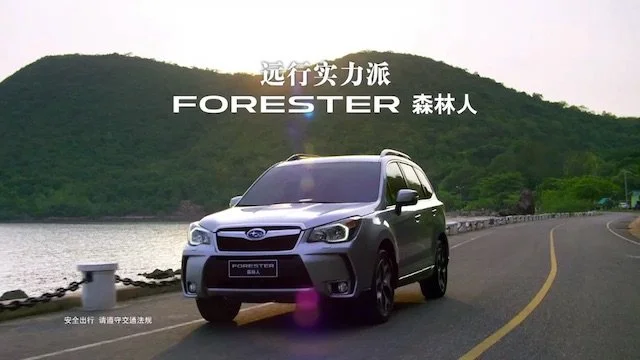 湖のそばの道路を走る黒のフォレスター車と後ろに山と水域