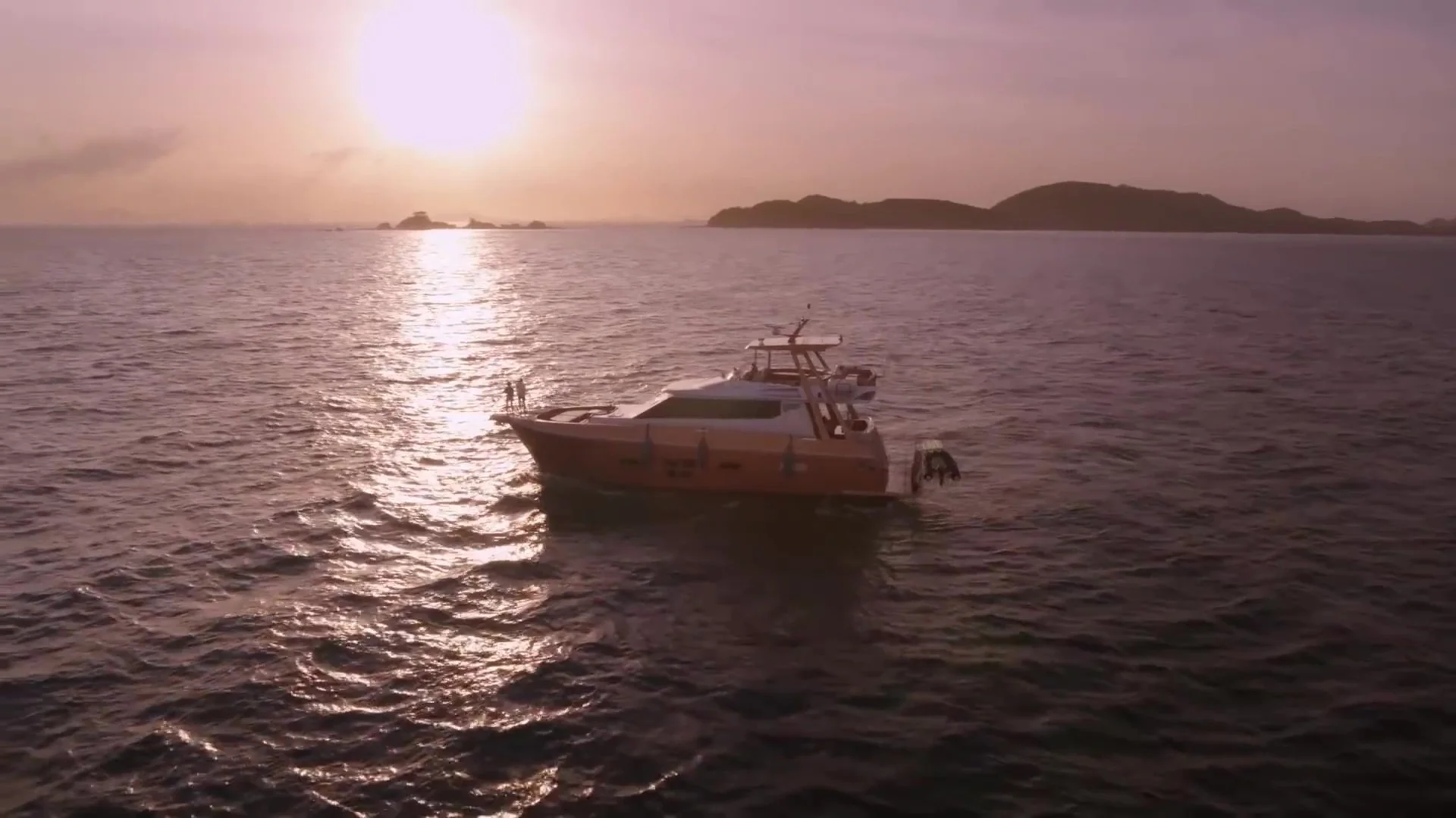 夕暮れ時の海の上に停泊しているモーターボートと、遠くに見える島々