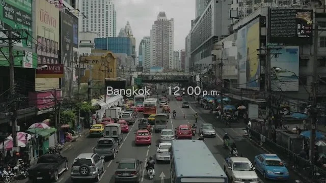 バンコクの都市の道路の交通渋滞の写真。車やバイクが混在し、多くのビルと大型広告が周囲に立ち並ぶ繁華な都市風景。