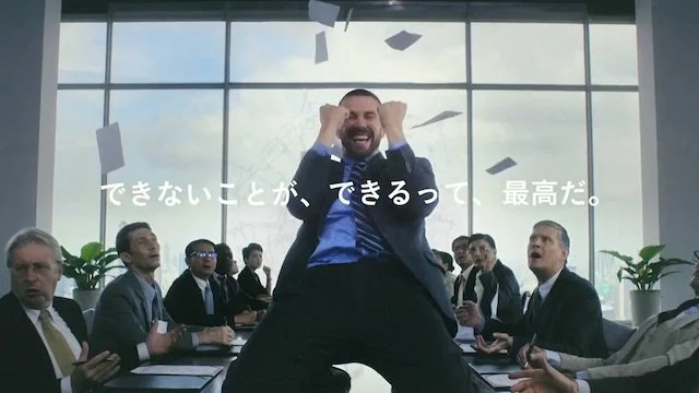 会議室で歓喜する男性と周囲の人々