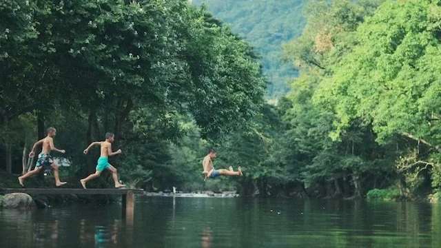 川の上で友達と飛び込みをする若い男の子たち