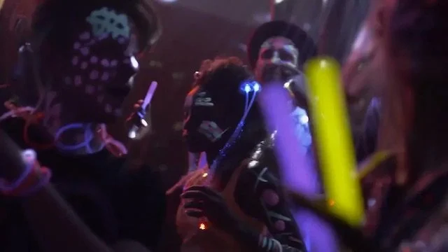 夜のパーティーで人々が光るスティックを持って楽しんでいる様子