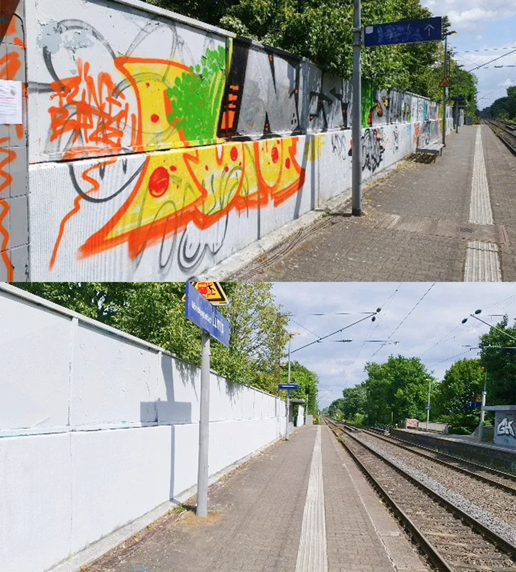 Bahnsteig an einem stillgelegten Bahnhof mit Graffiti an einer Wand und Bahnsteigen, Straßenlaternen und Bahnleitungen im Hintergrund.