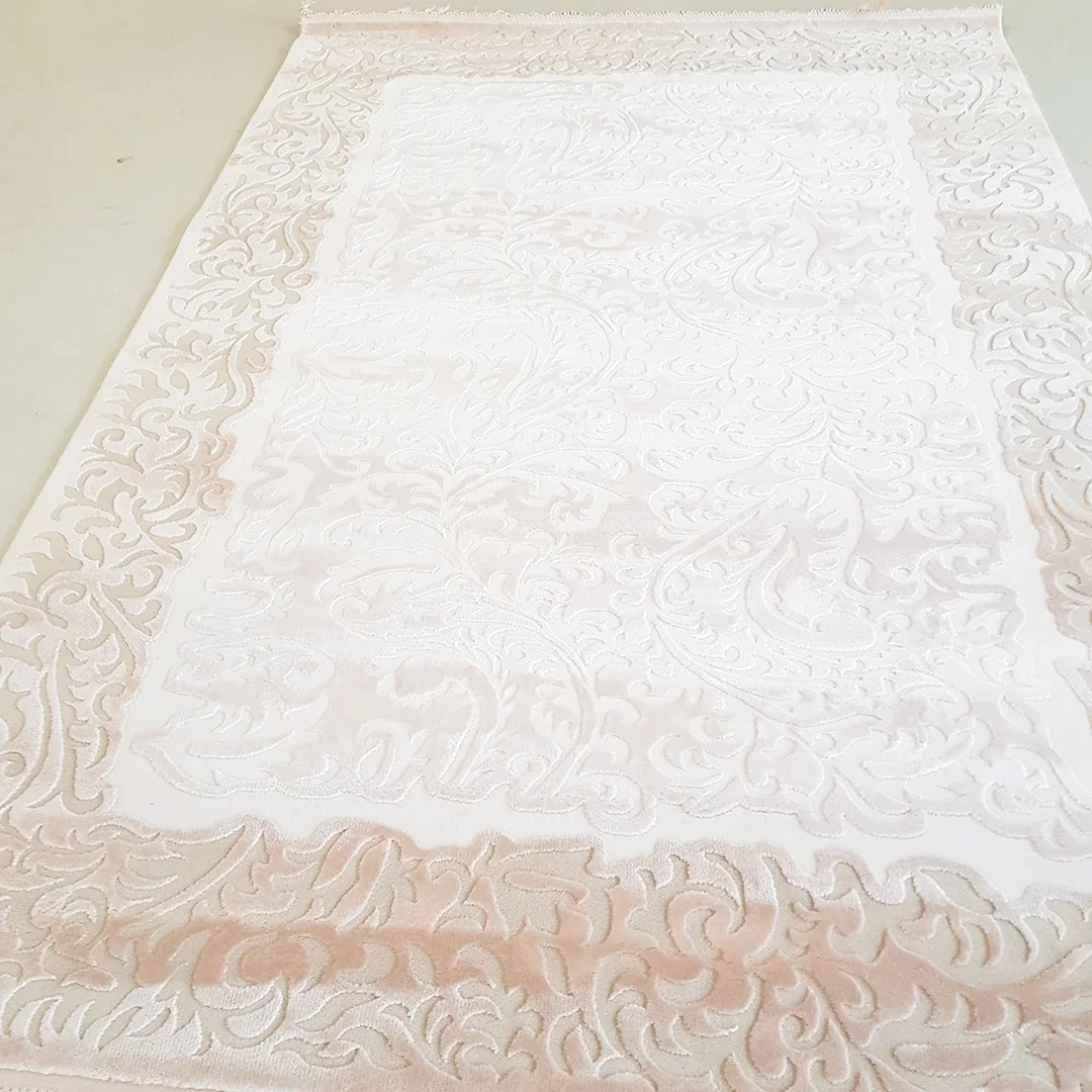 Ein weißer, verzierter Teppich mit eleganten, geschwungenen Mustern und einer filigranen Bordüre.
