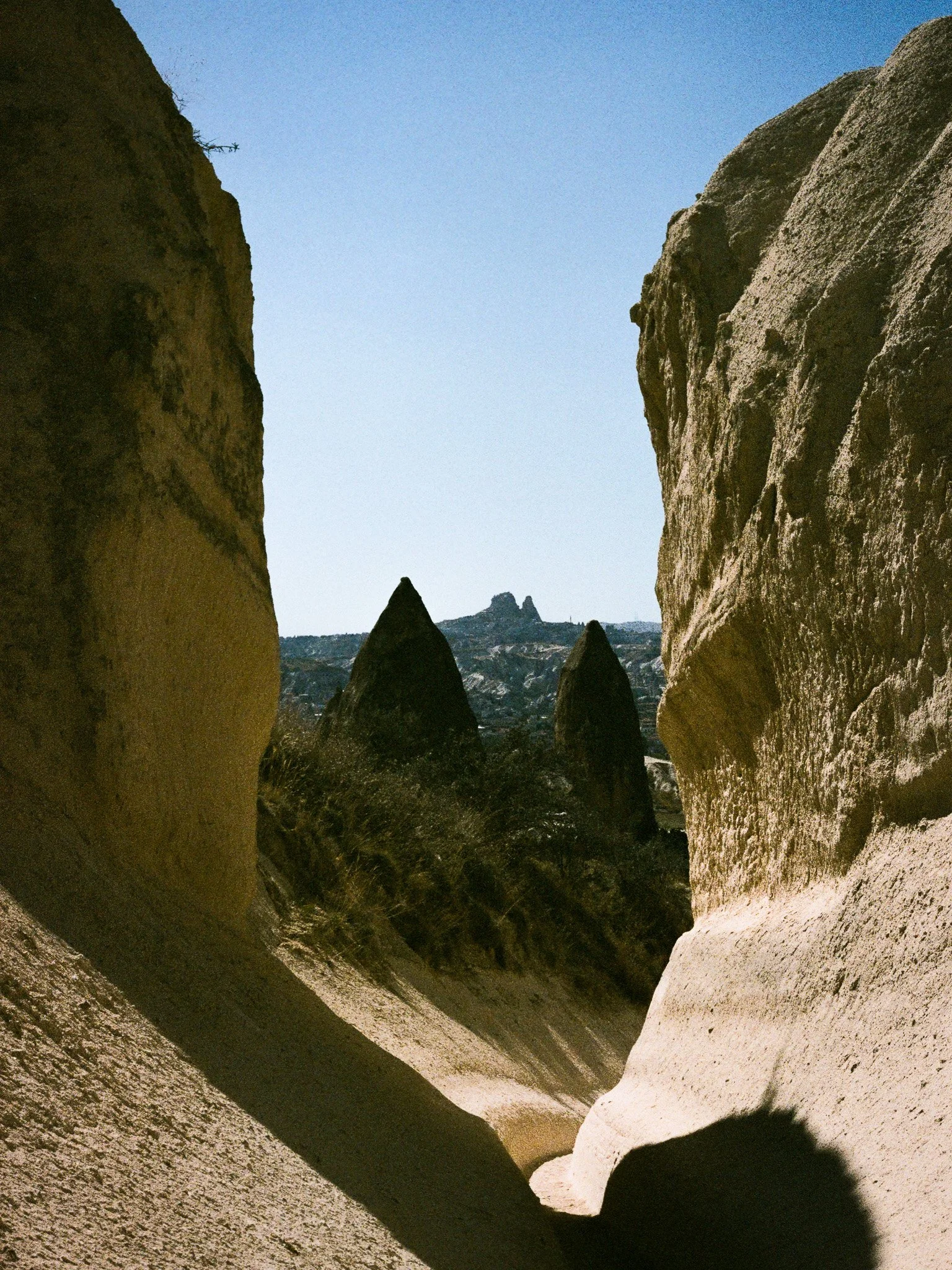 A view of rocky formations and cliffs in a desert landscape with a clear blue sky.