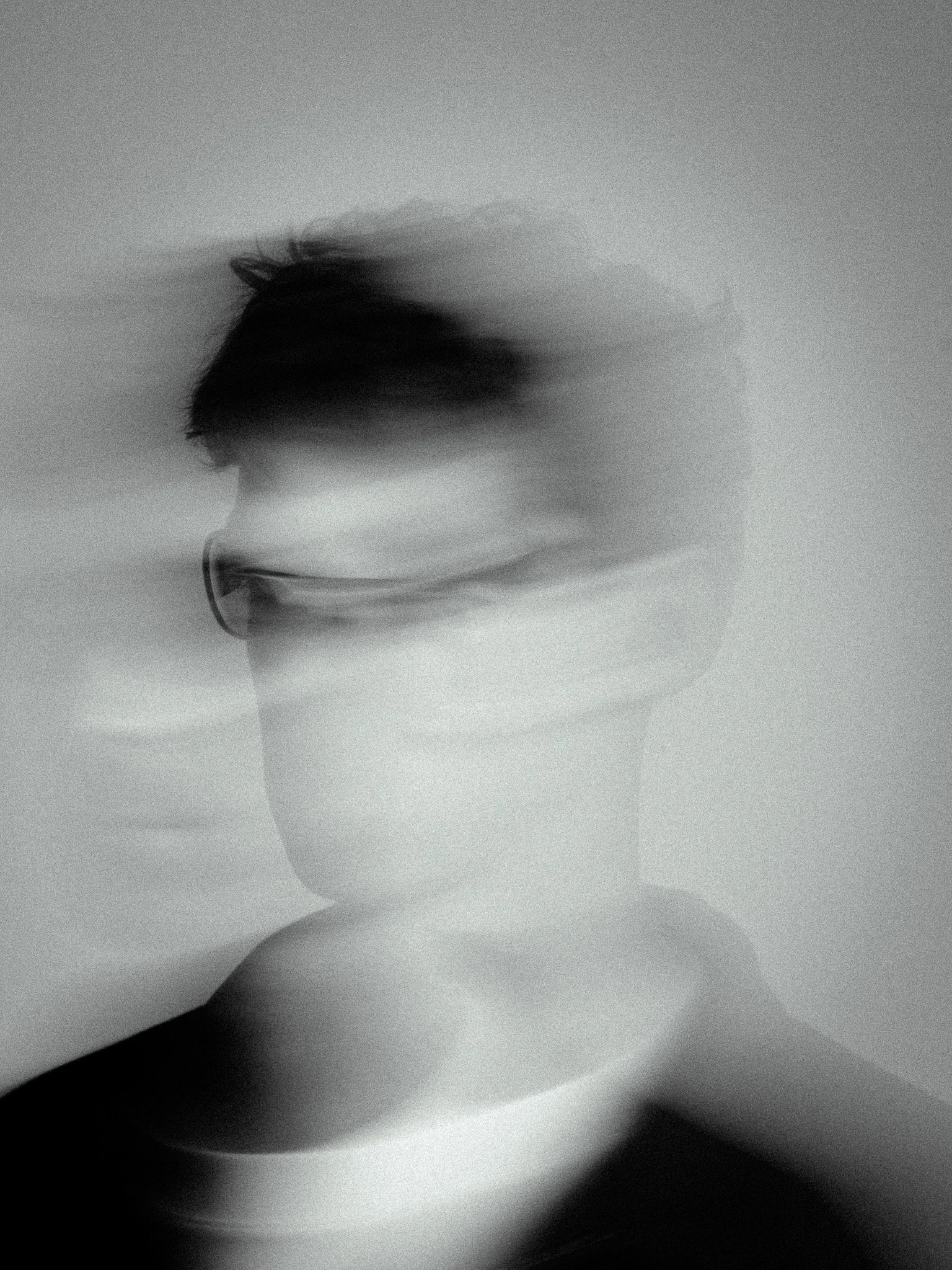 Blurry black-and-white portrait of a person wearing glasses, with motion blur effects.
