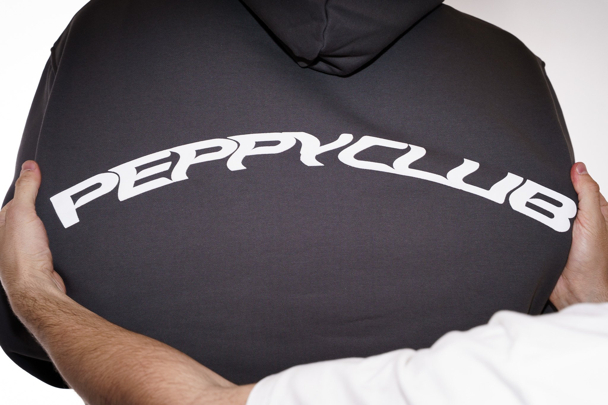 Person holding a grey hoodie with the Peppycub logo printed on it.