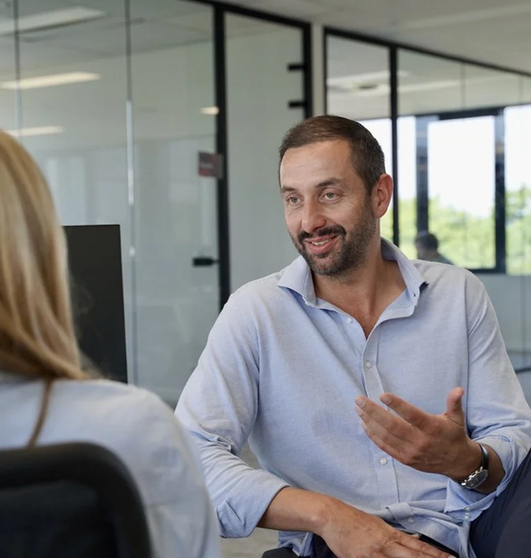 A man talking to a woman in a professional office setting.