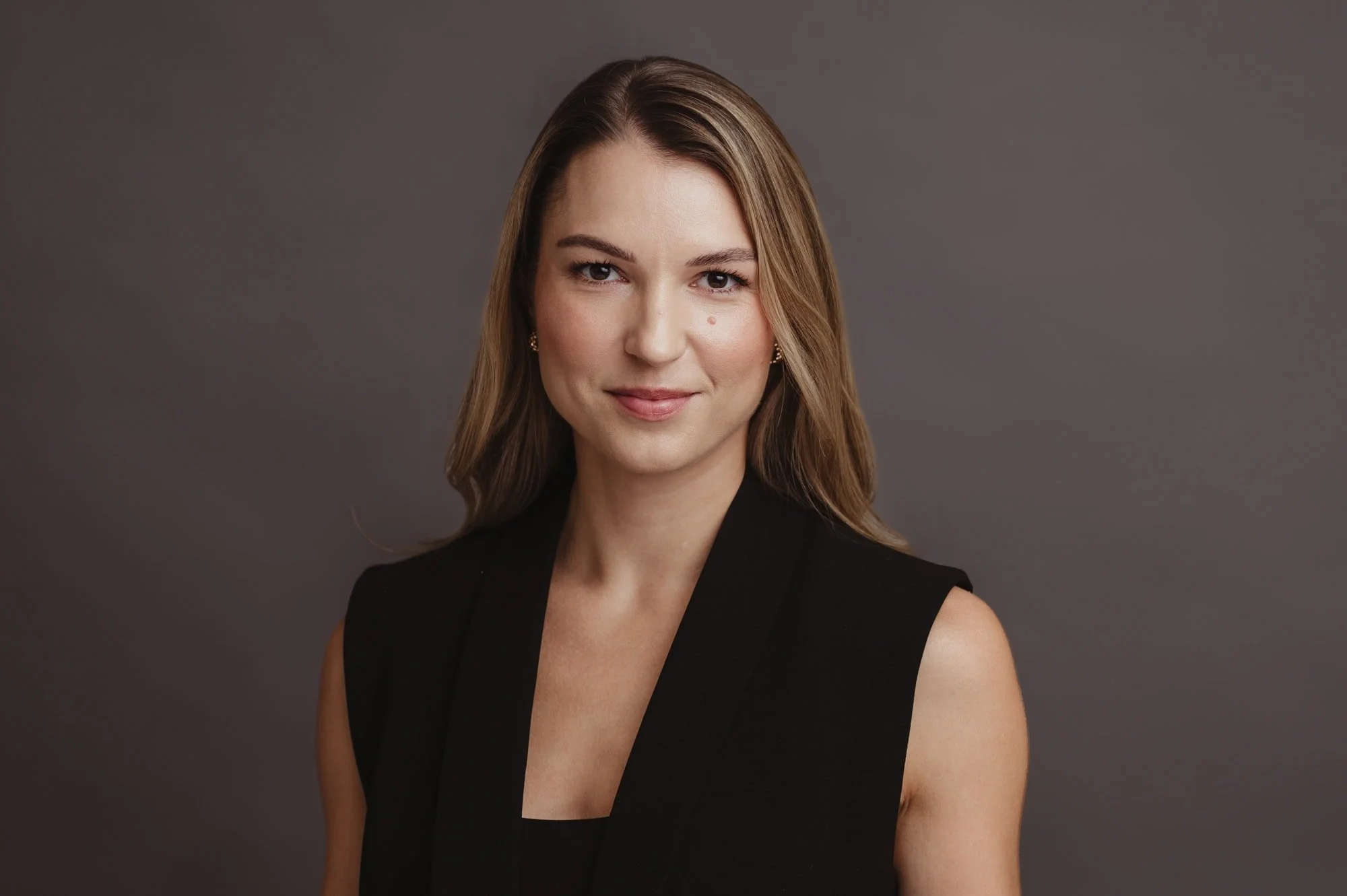 Professioneller Headshot einer Frau mit schwarzer Weste und dezentem Lächeln, Business-Fotografie Zürich.