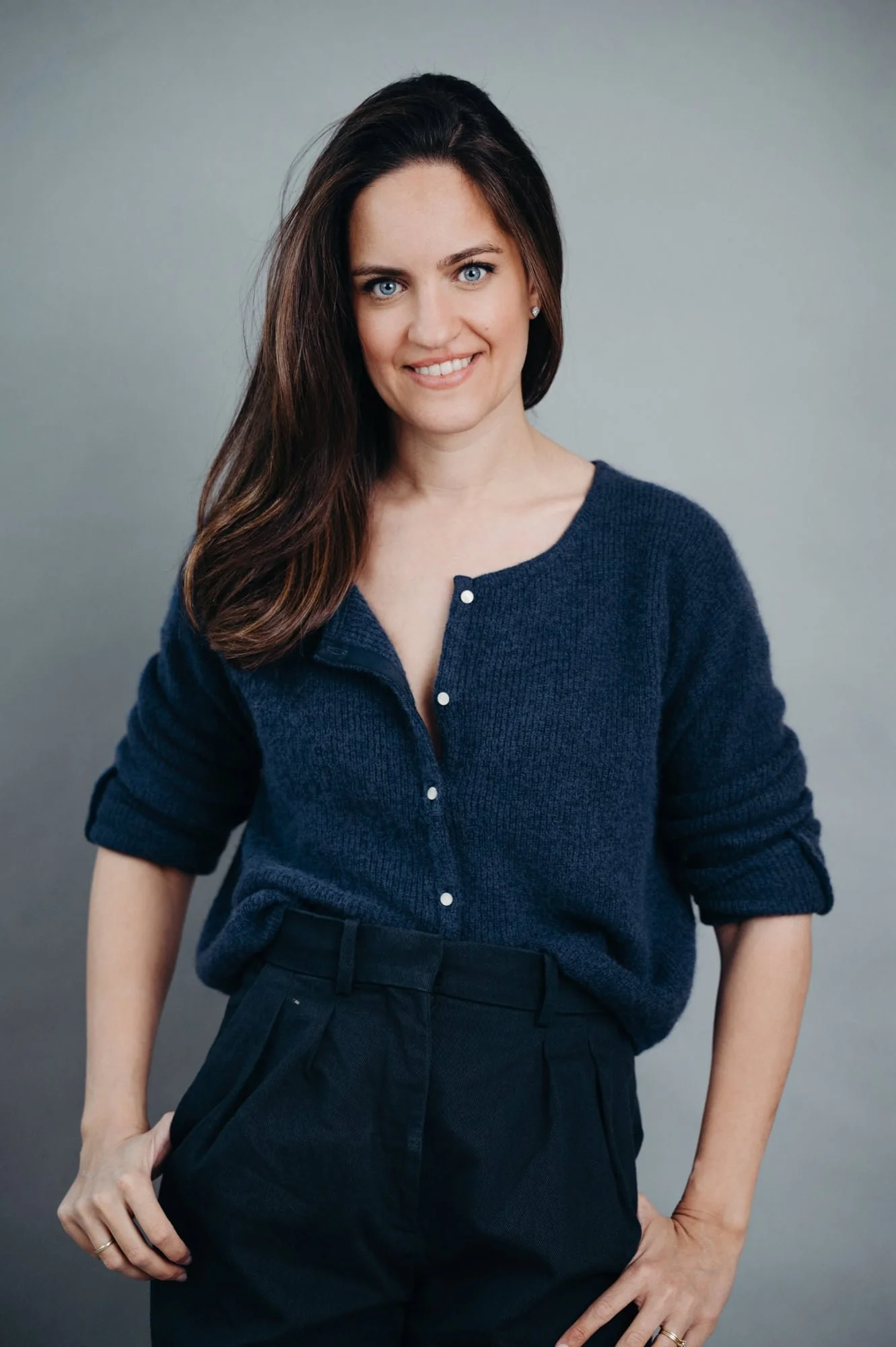 Authentisches Business-Lifestyle-Porträt einer Frau im dunkelblauen Cardigan, stehend in Zürich.