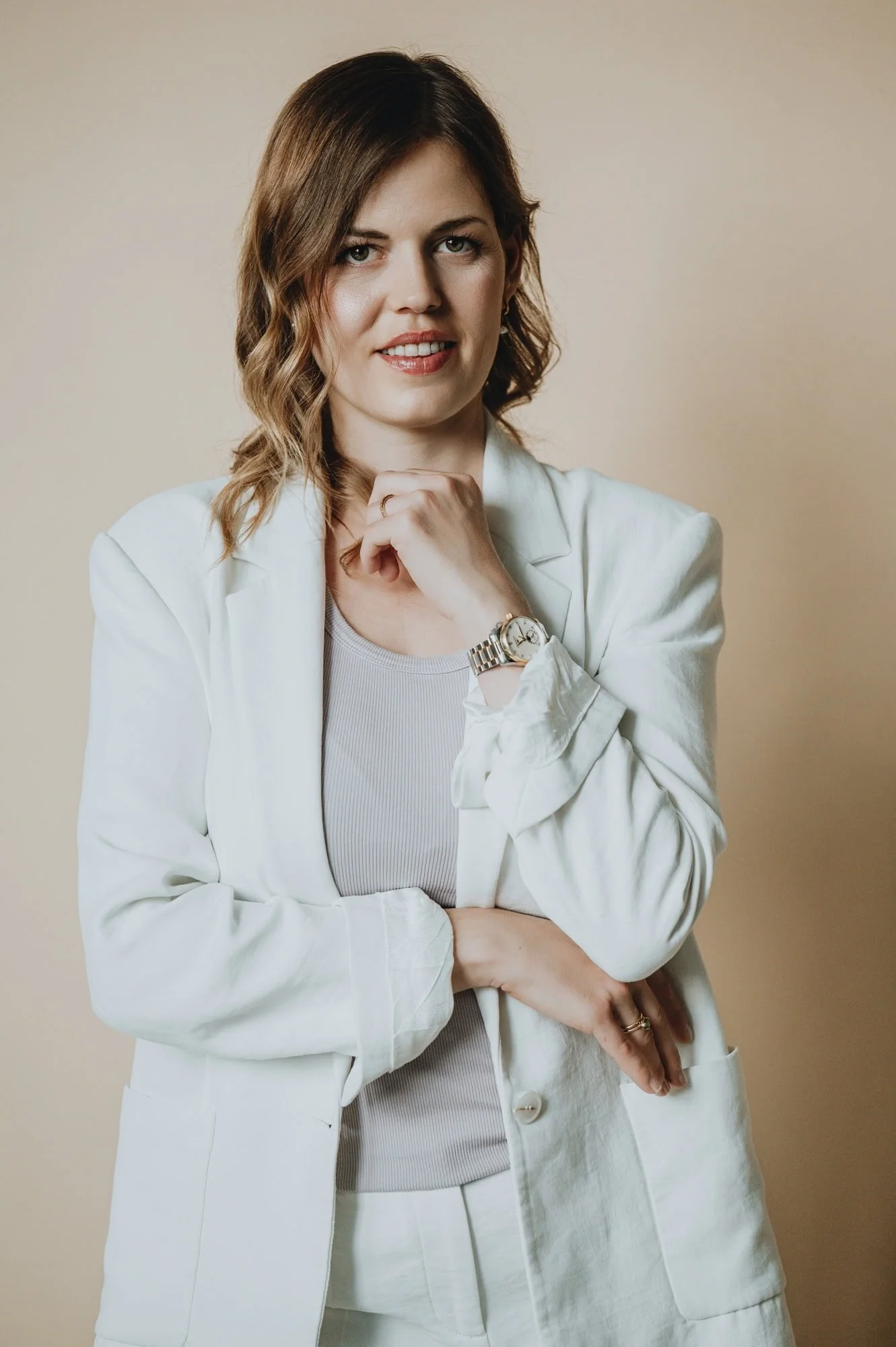 Woman wearing white suit looking into camera in headshot session, Zurich