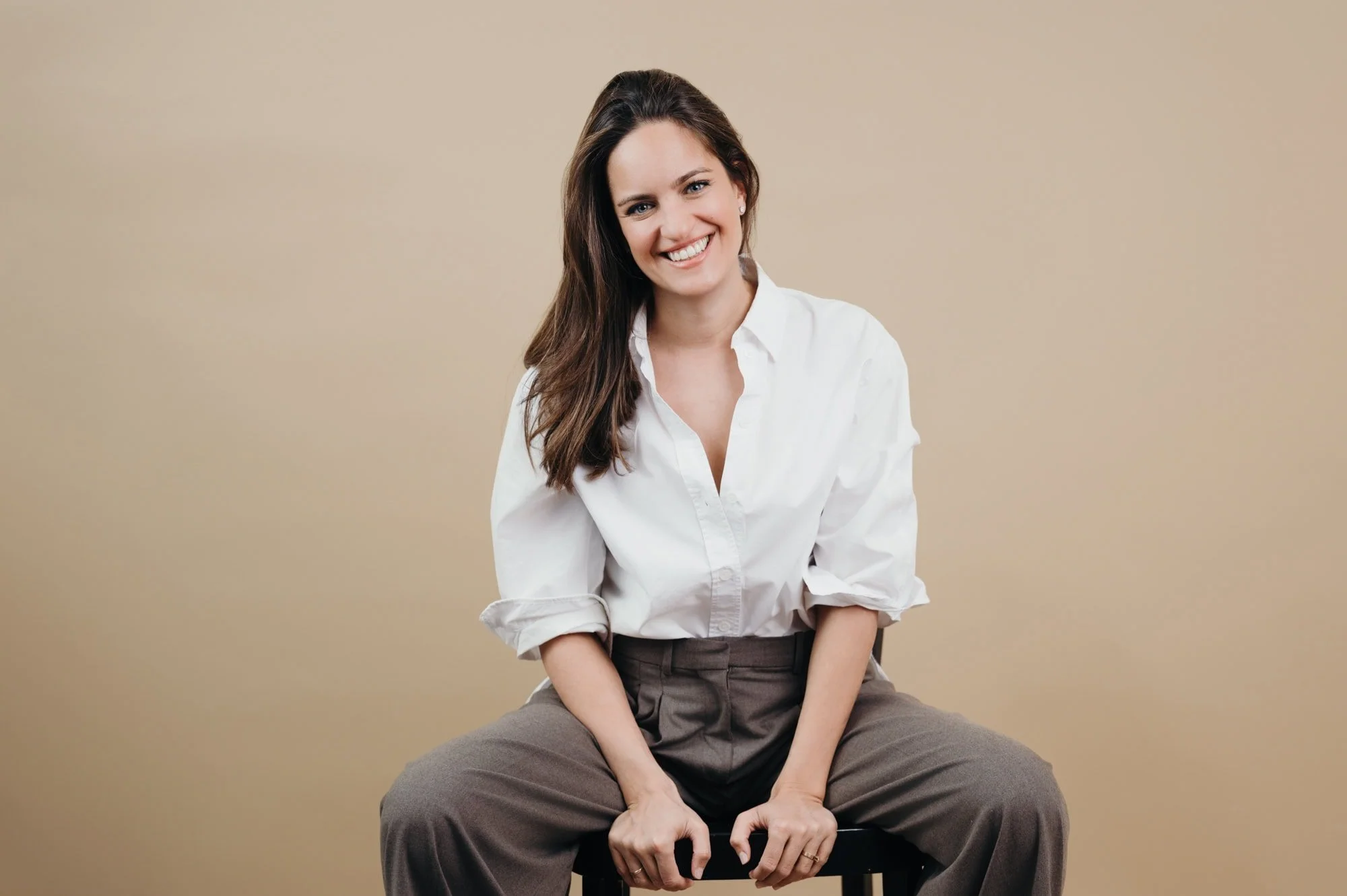 Business Porträt einer Frau in weißer Bluse, sitzend mit direktem Lächeln, Zürich.