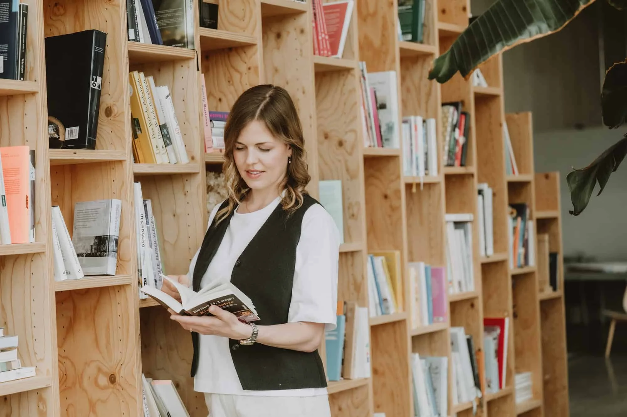 Frau blickt in ein Buch vor einem Bücherregal in einem Fotostudio in Zürich