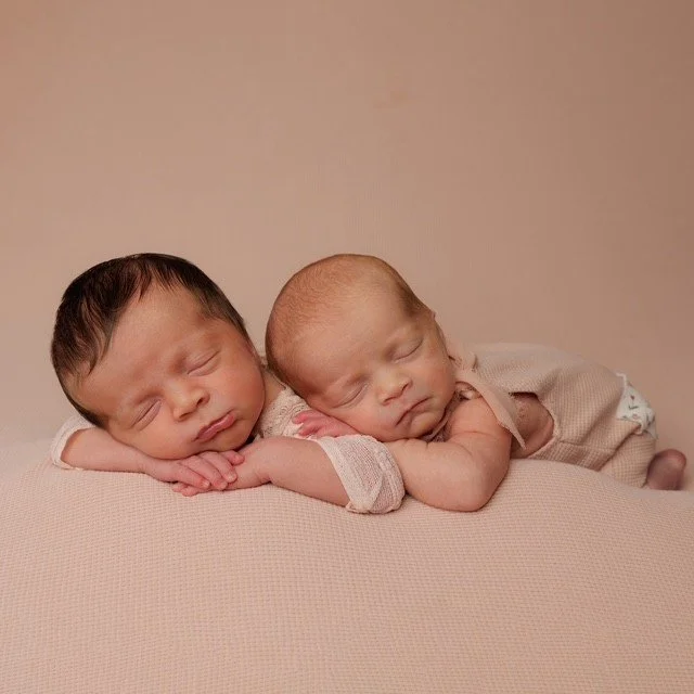 Two new born babies sleeping side by side on a soft surface with their heads touching. Photography at Studio 5 by JK Photography, Carlisle, Cumbria.