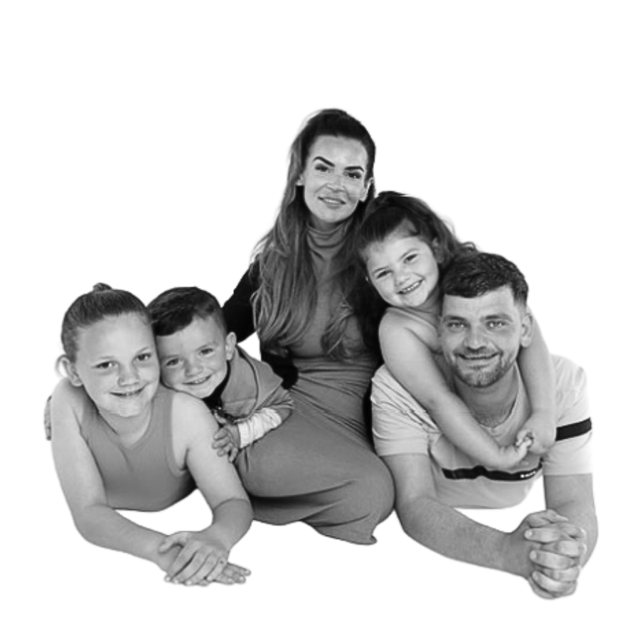 Black and white photo of a happy family with three children, a woman, and a man, all smiling and posing closely together.