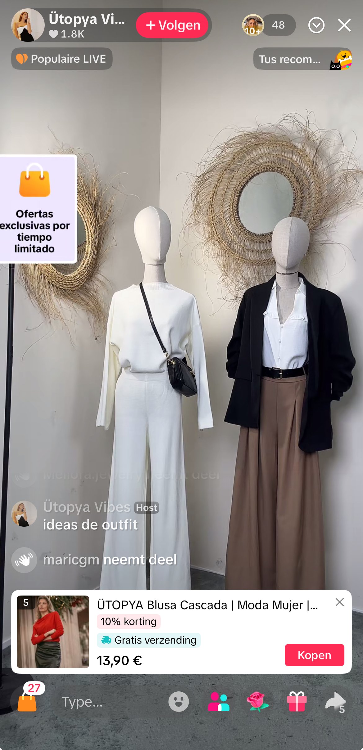 Two mannequins dressed in stylish outfits displayed against a white wall with decorative woven mirrors. The left mannequin wears an all-white outfit with wide-leg pants and a sweater, carrying a small black purse. The right mannequin wears a white shirt, brown wide-leg pants, and a black jacket. The scene appears to be in a boutique or clothing store.