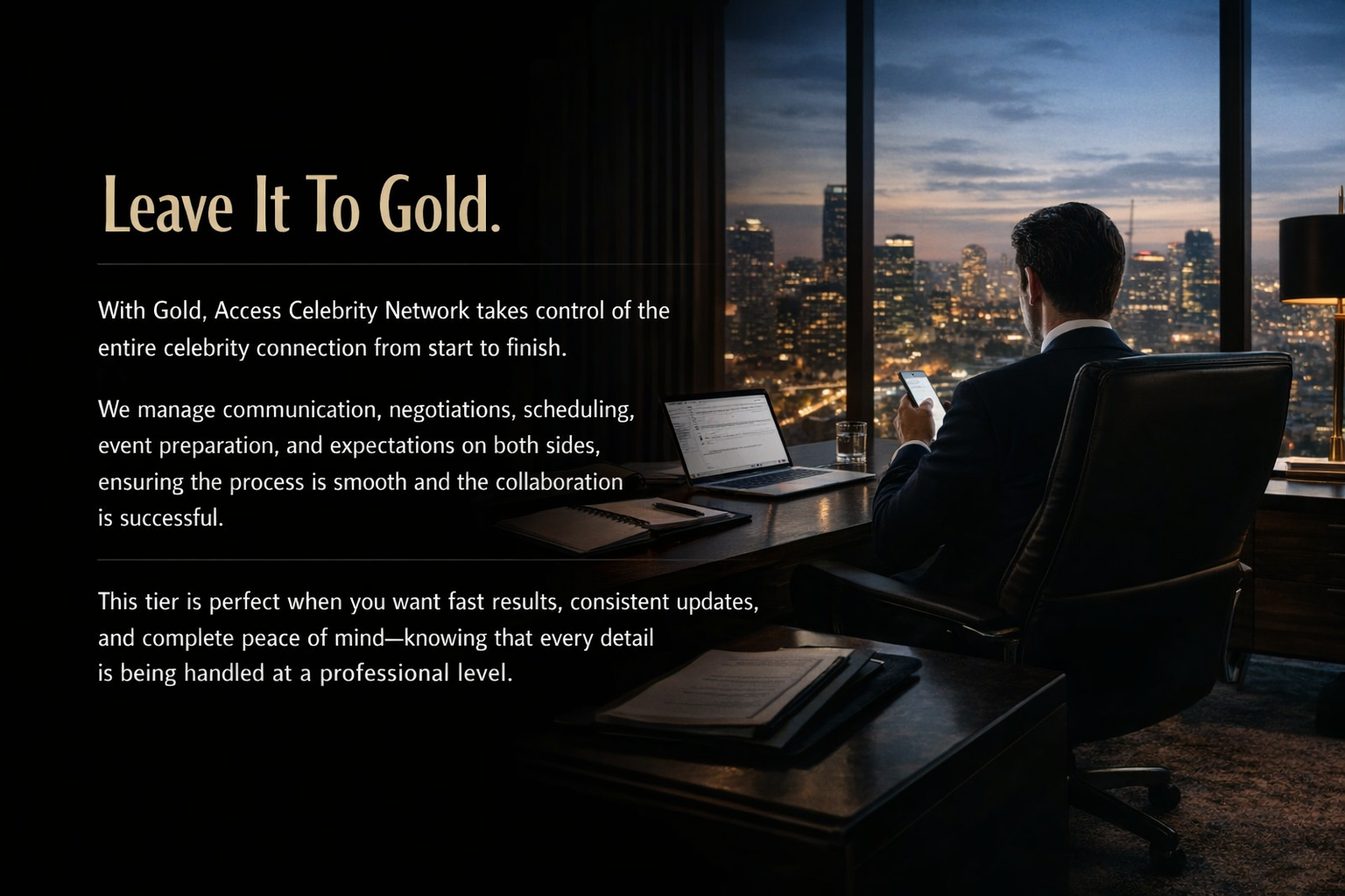 A man in a suit sitting in a modern office at night with a view of a city skyline through large windows, working on a laptop and looking at a smartphone, with a glass of water on the desk.