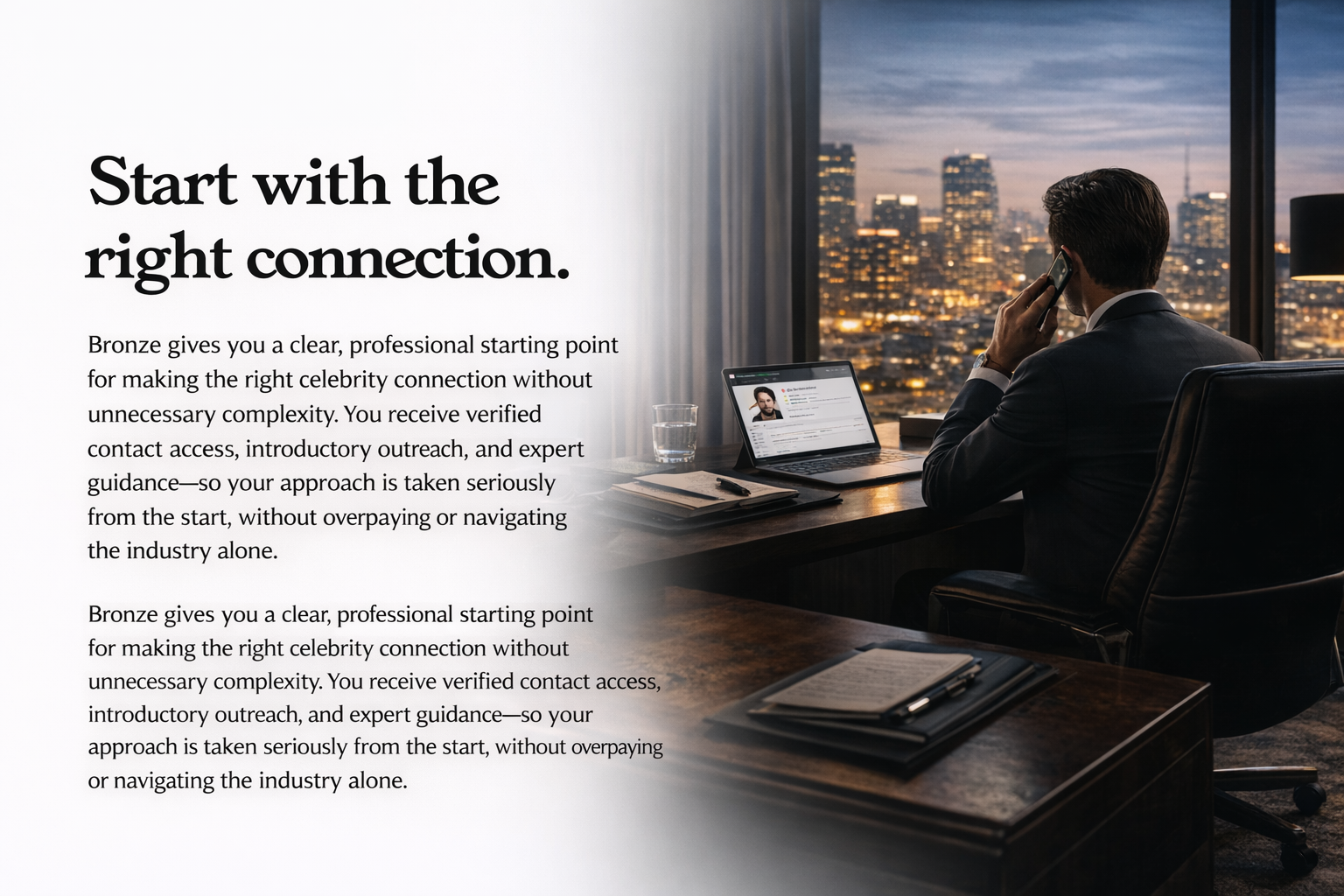 A business professional in a suit sitting at a desk in a high-rise office, talking on the phone, with a city skyline at dusk visible through large windows. The desk has a laptop, glass of water, and a stack of papers.