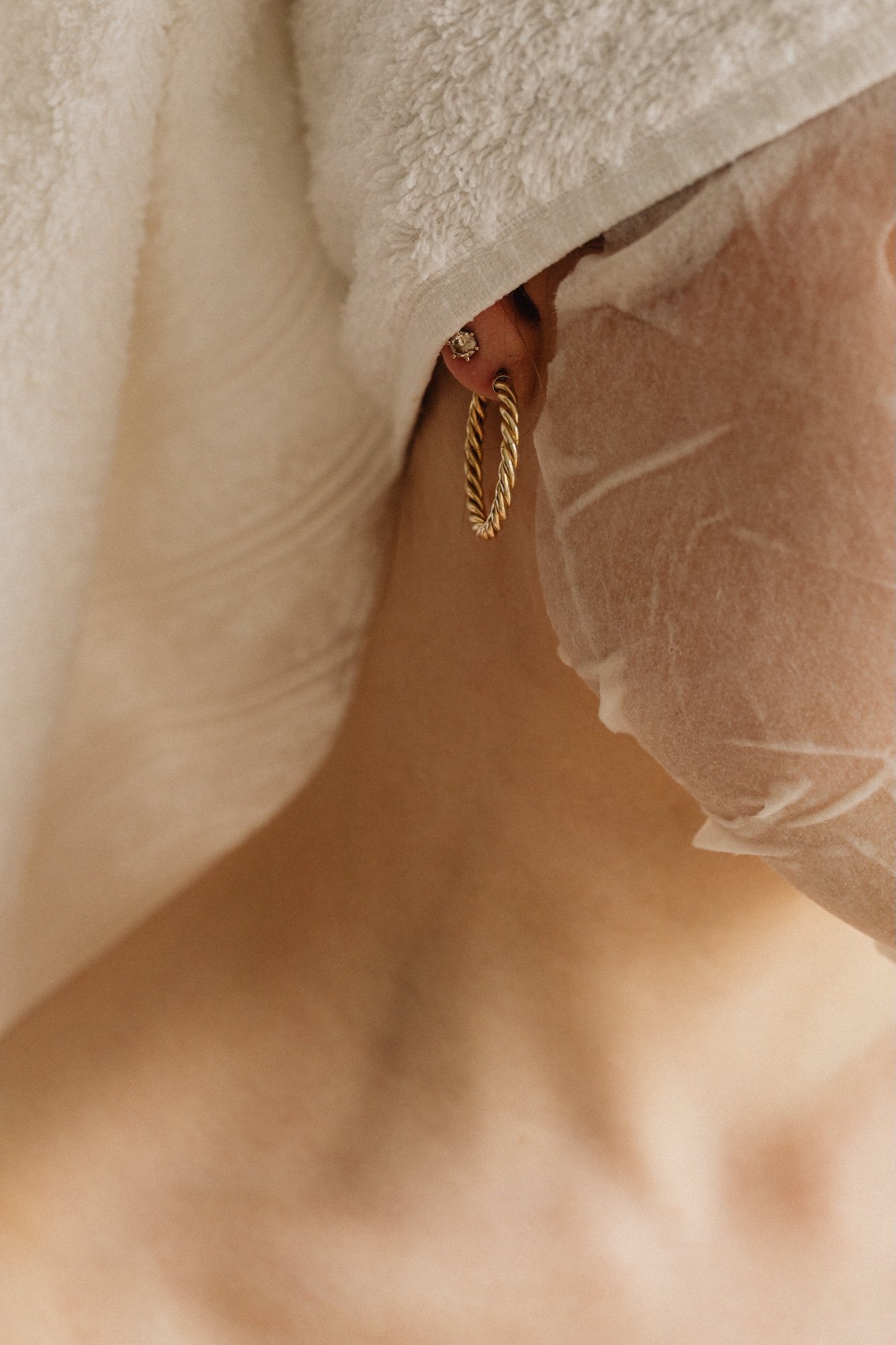 Lähikuvassa ihmisellä on kultaiset korvakorut ja korvakoruja, hän on kauneushoitolan asiakas.