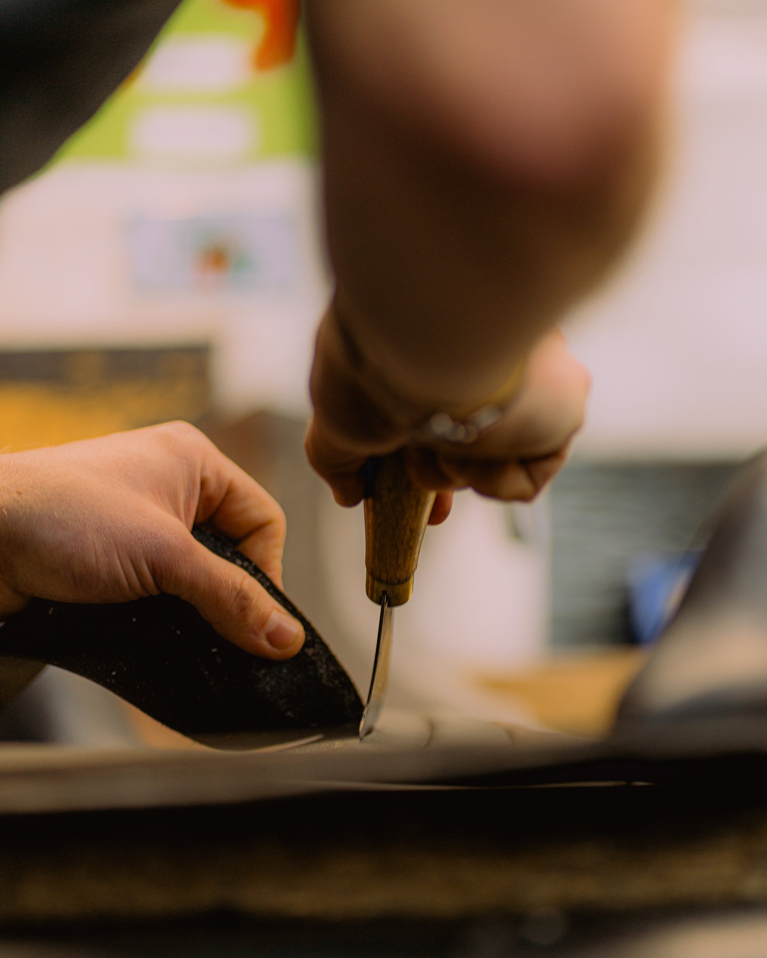 A skilled artisan cutting high-quality leather by hand in the Custom Saddlery workshop in England, preparing materials for handcrafted saddles and equestrian accessories.
