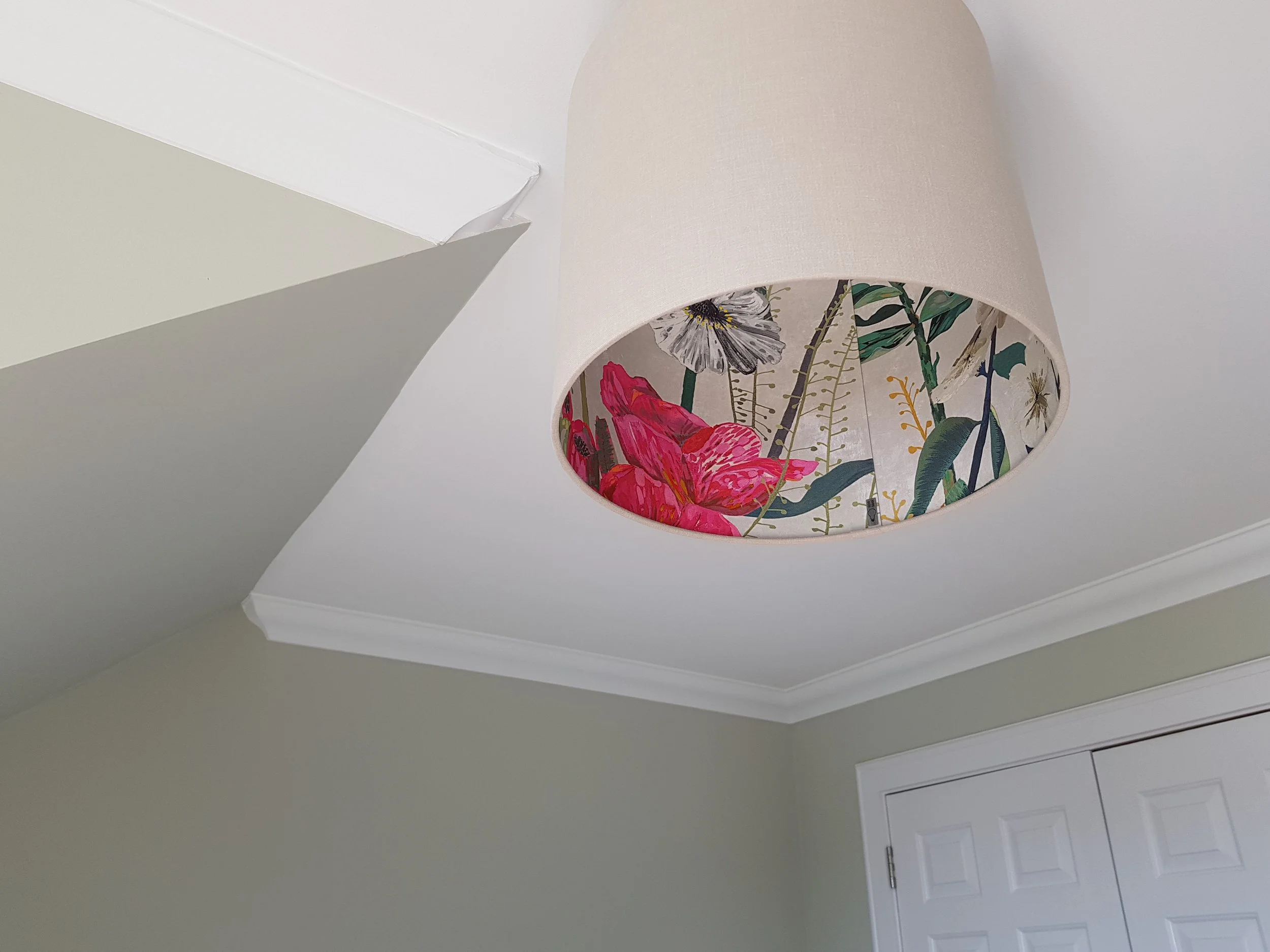 Ceiling light fixture with a floral interior shade showing pink, white, and green botanical patterns.