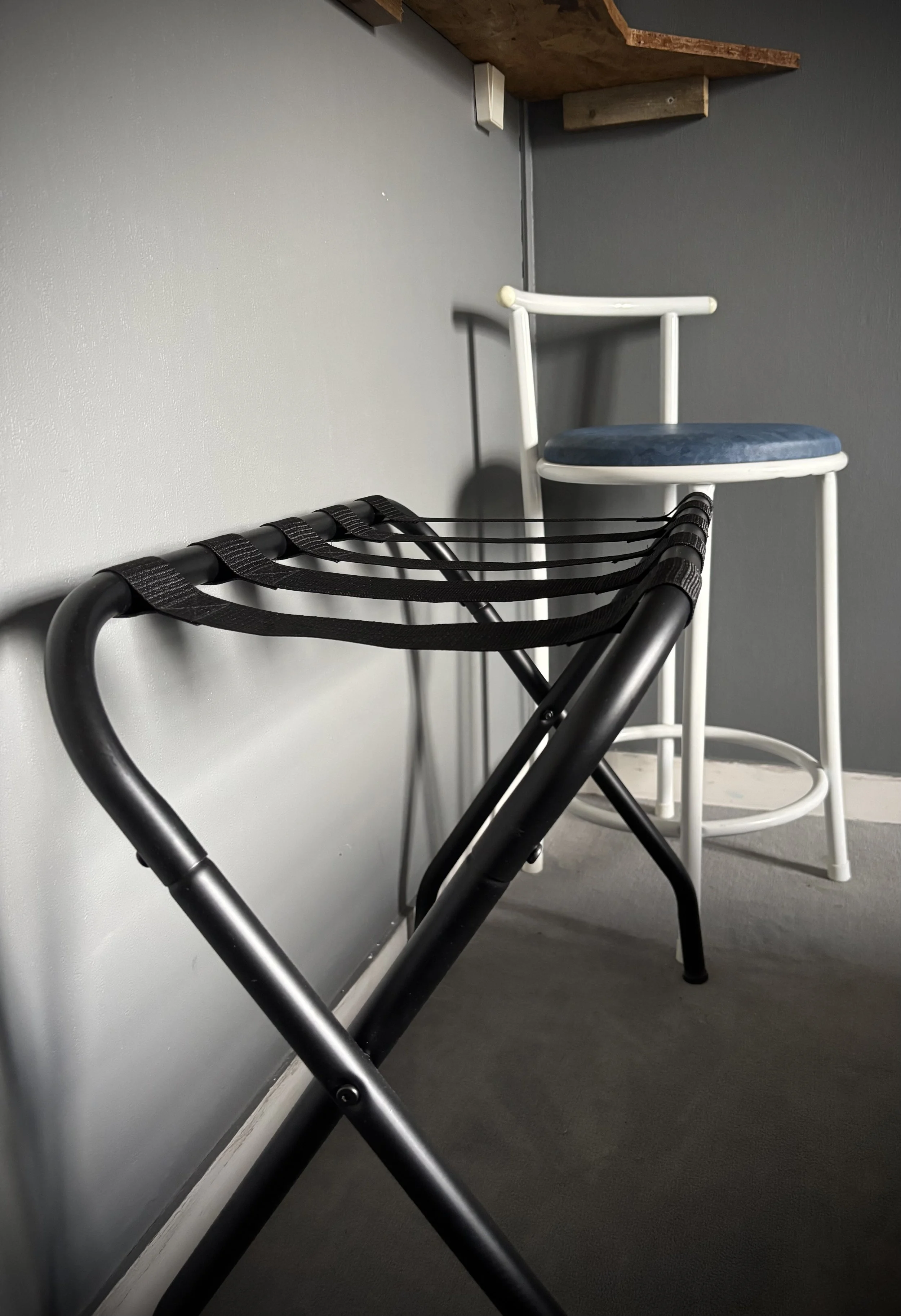 Chaise blanche et tabouret avec un coussin bleu dans une pièce avec un mur gris