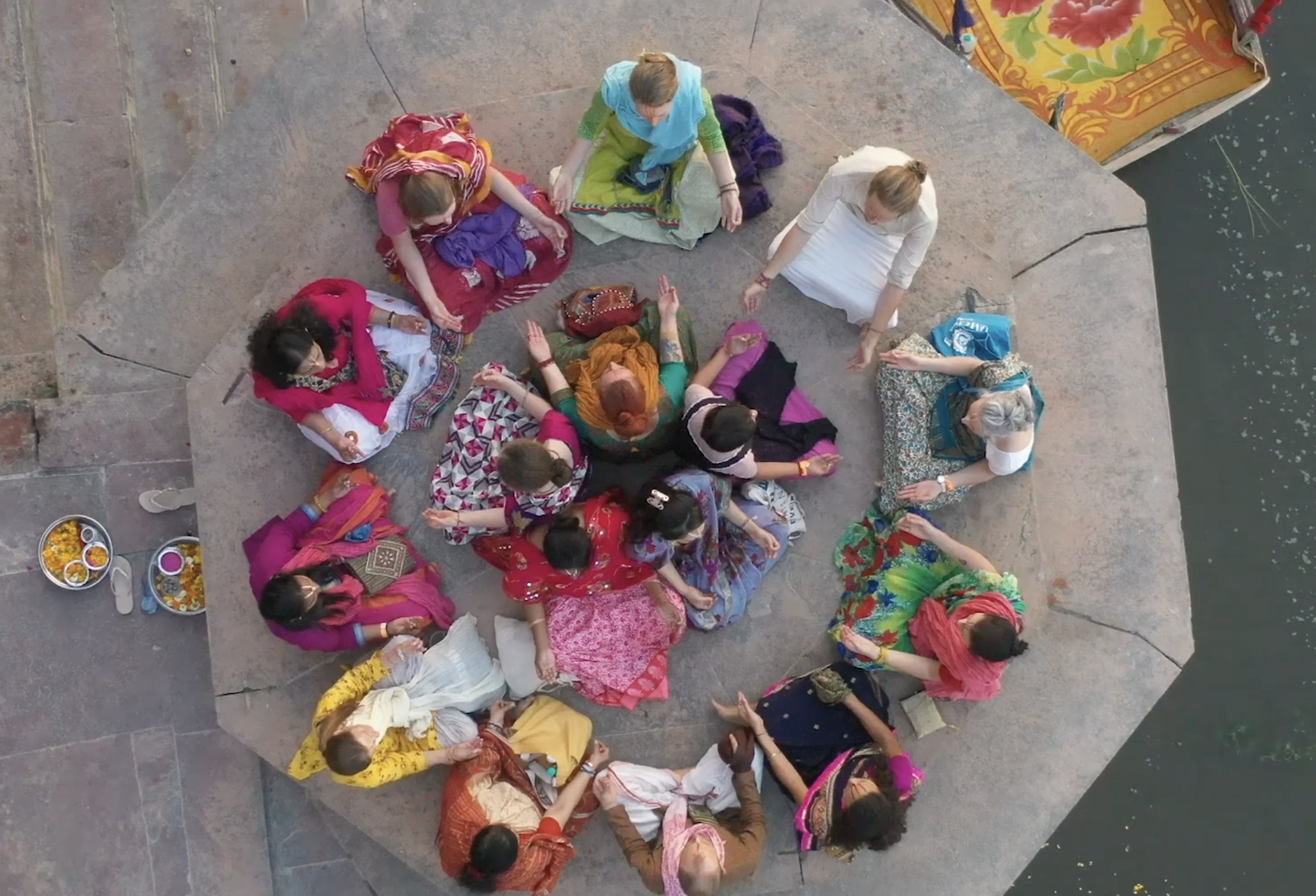 Om chanting, groupe de personnes en vêtements traditionnels indiens formant un cercle autour d'une personne au centre, probablement pour une prière ou une cérémonie.