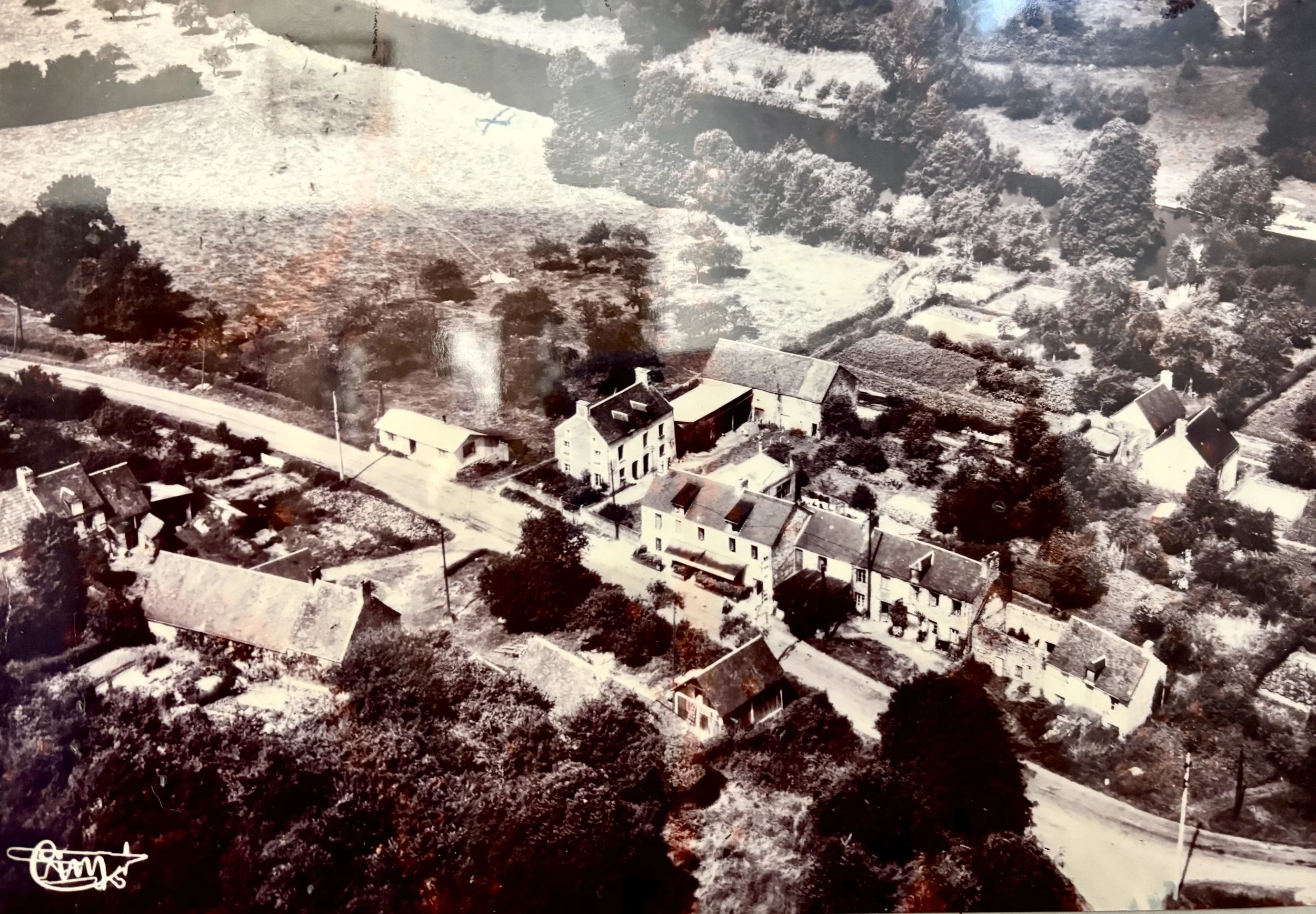 Une vue aérienne du petit village rural de Saint Christophe avec plusieurs maisons, arbres et routes, en noir et blanc.