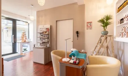 Salon de réception avec fauteuils, table avec des objets, étagères et décoration végétale.