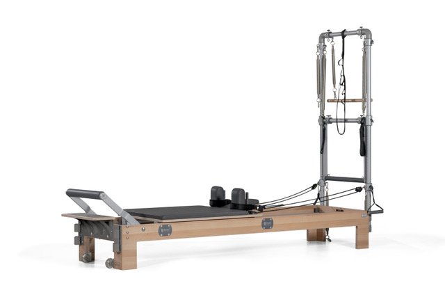 A Pilates reformer machine with a wooden frame, padded platform, and various pulleys and straps for exercise.