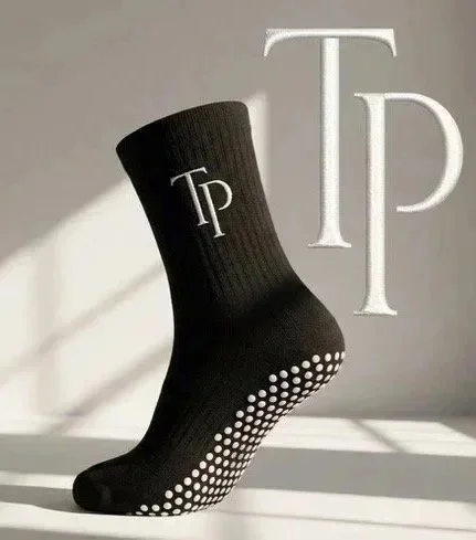 A black sock with white Polka dots on the heel and toe, featuring the initials 'TP' on the ankle, and large white 'TP' letters in the background.