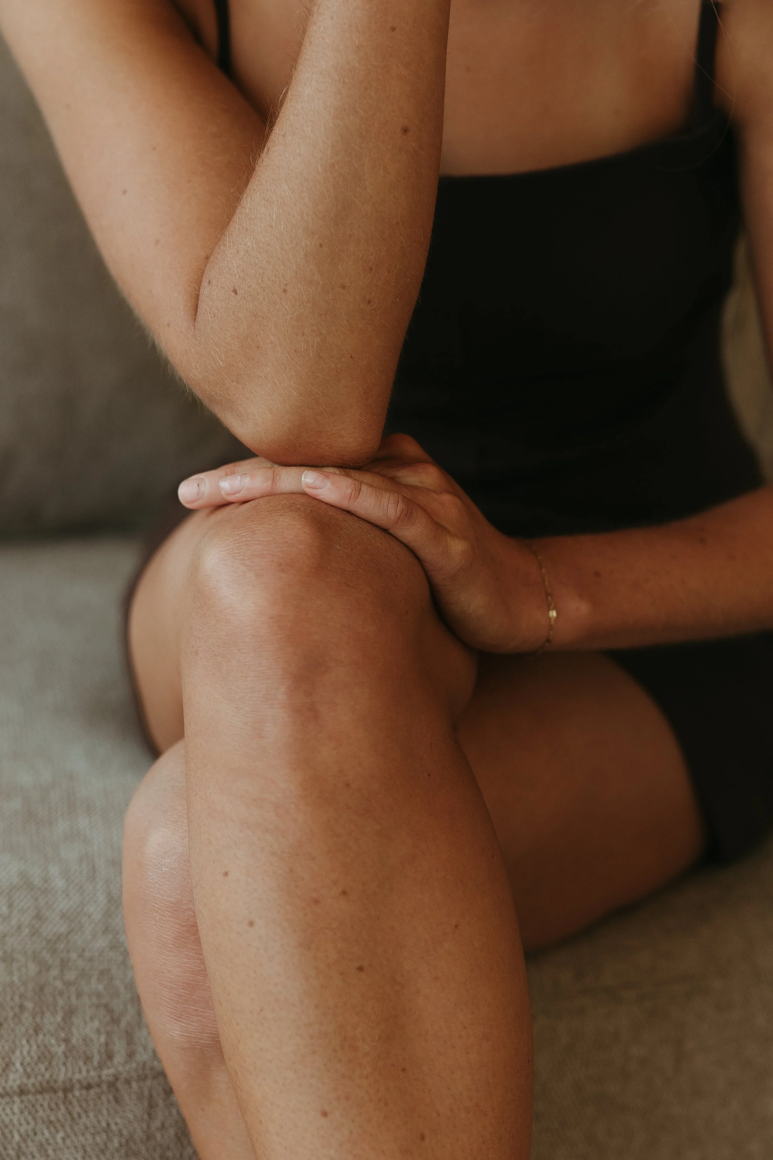 Photo of a person's legs and feet with red toenail polish, standing on a white tiled floor near a white curtain.