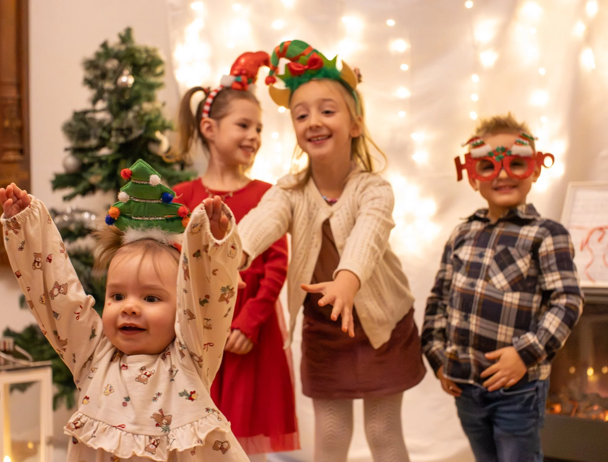 Kinder feiern Weihnachten in festlicher Atmosphäre mit Weihnachtsdekoration, Lichterketten und einem Weihnachtsbaum, tragen festliche Kleidung und Spaß. 