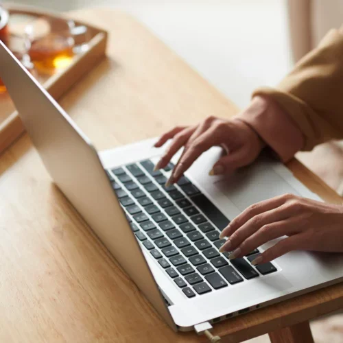 Personne tapant sur un ordinateur portable sur une table en bois.