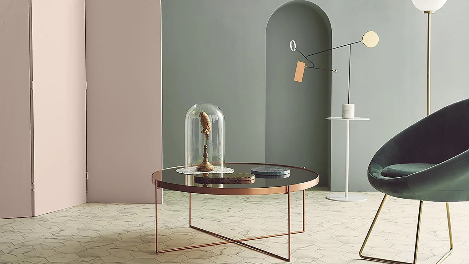 Intérieur moderne avec un meuble en verre contenant une sculpture, une table en métal, une lampe sur pied blanche, un fauteuil noir avec des jambes en métal doré, murs en tons pastel, sol en marbre clair.