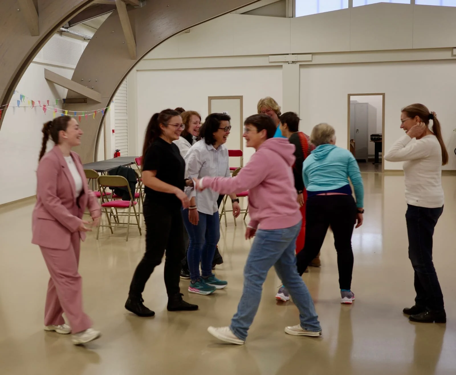 Gruppo di persone che ballano insieme in una sala, sorridendo e divertendosi.