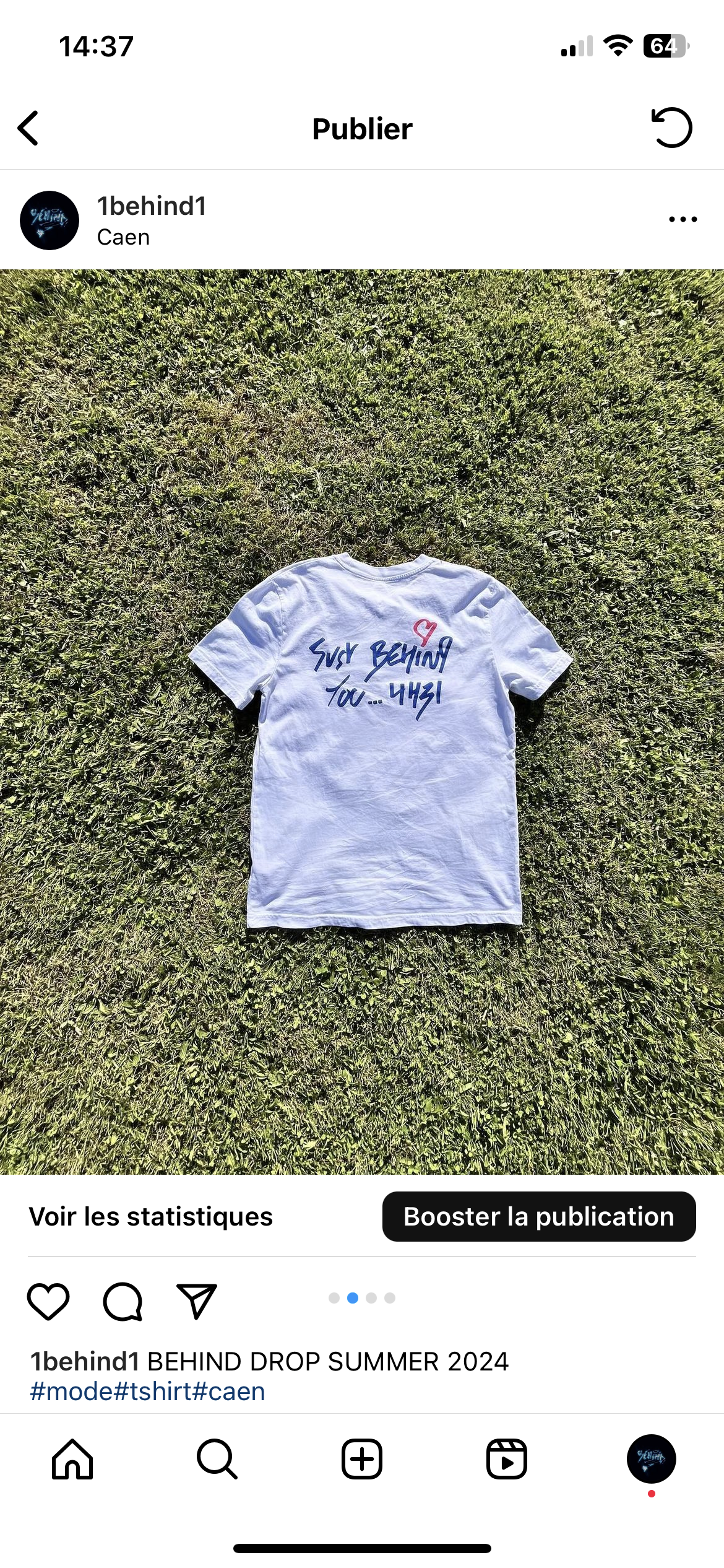Un t-shirt blanc posé sur de l'herbe, avec des inscriptions en bleu et un cœur rouge au dos.