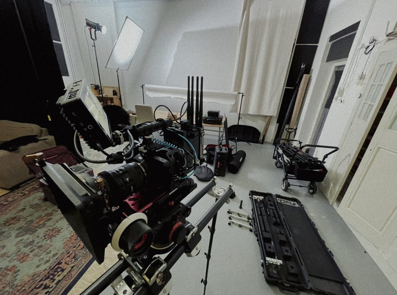 Een filmset met camera, licht, koffer, trolley, en ander filmtechnisch materiaal in een kamer.