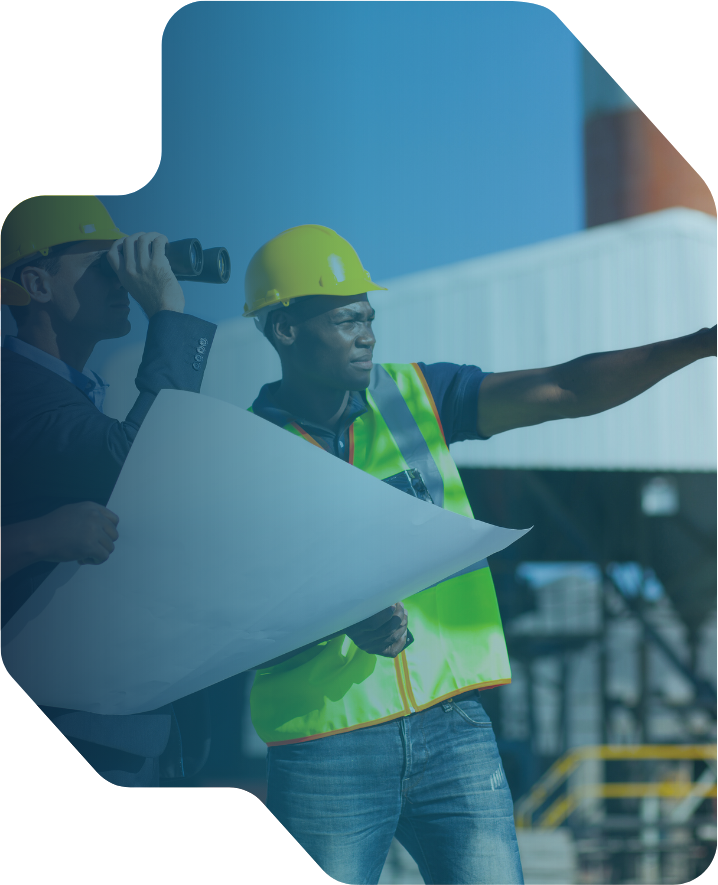 Two construction workers in yellow helmets and safety vests at a work site, one holding a rolled-up blueprint and the other pointing into the distance with binoculars.